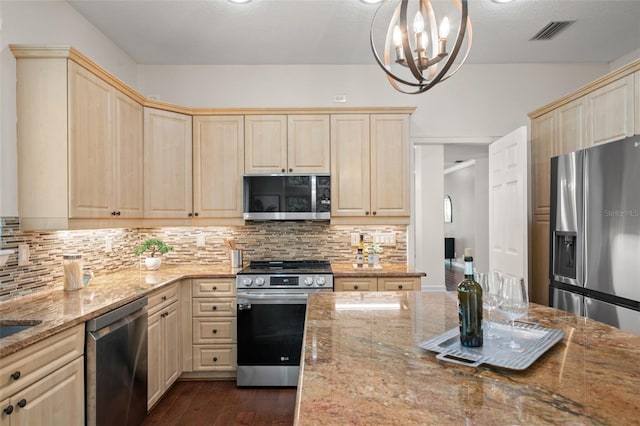 kitchen featuring light stone counters, stainless steel appliances, hanging light fixtures, and an inviting chandelier