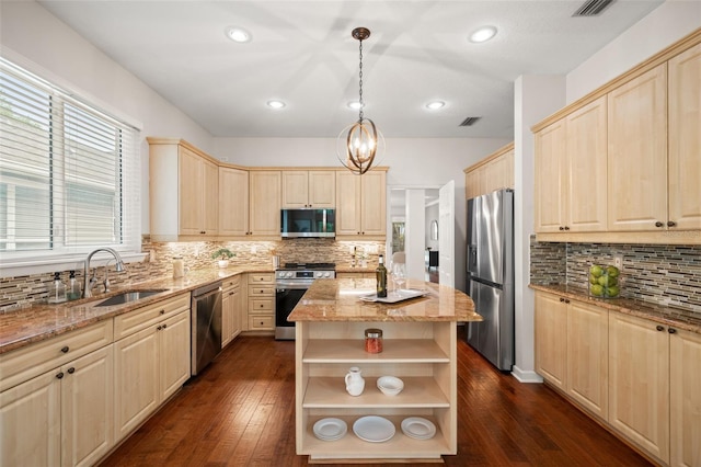 kitchen with appliances with stainless steel finishes, dark wood-type flooring, sink, decorative light fixtures, and a kitchen island