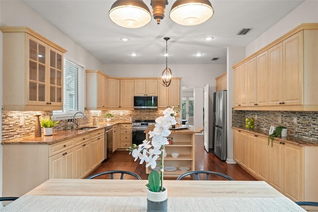 kitchen featuring light stone countertops, appliances with stainless steel finishes, dark wood-type flooring, light brown cabinets, and pendant lighting