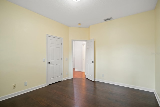 empty room with a textured ceiling and dark wood-type flooring