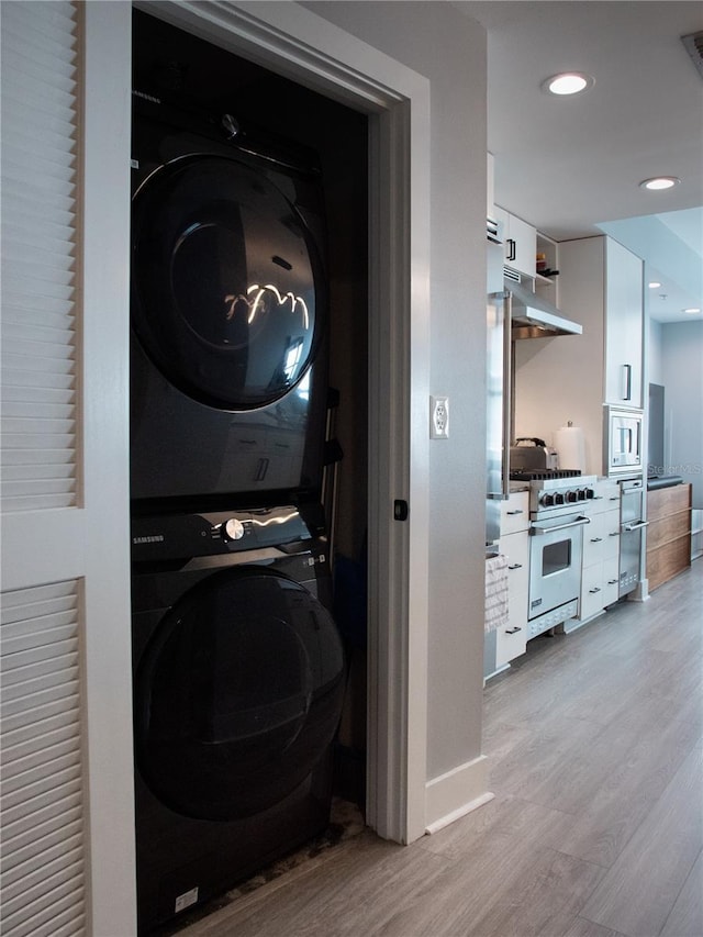 washroom featuring recessed lighting, stacked washer and clothes dryer, light wood-type flooring, and laundry area