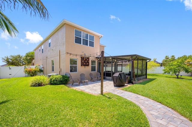 rear view of property featuring a lawn, a sunroom, and a patio