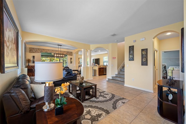 tiled living room with a chandelier and washer / dryer