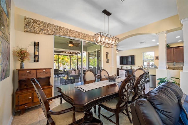 dining room featuring ceiling fan with notable chandelier, light tile patterned flooring, and decorative columns