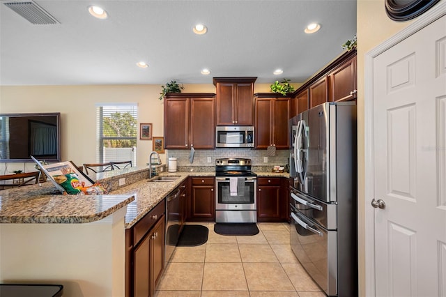 kitchen with kitchen peninsula, light stone counters, a breakfast bar, stainless steel appliances, and sink