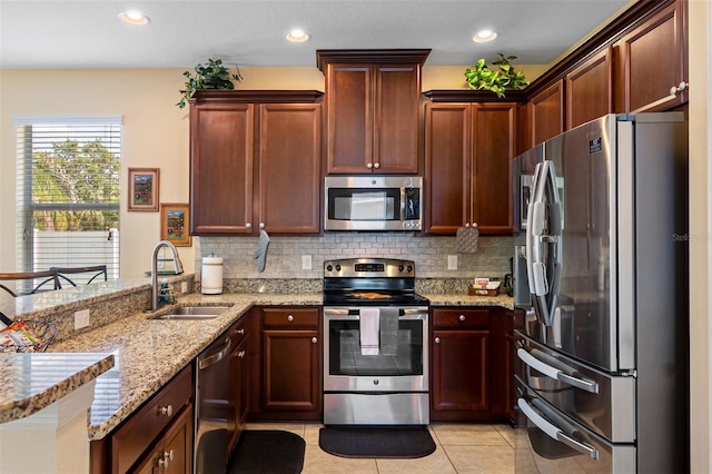 kitchen featuring light stone countertops, sink, stainless steel appliances, decorative backsplash, and light tile patterned floors