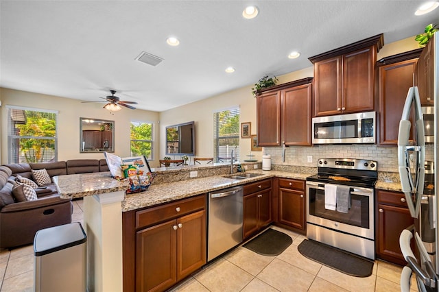 kitchen featuring kitchen peninsula, decorative backsplash, sink, and appliances with stainless steel finishes