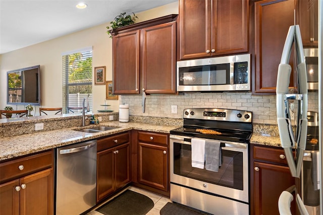 kitchen featuring backsplash, stainless steel appliances, light stone counters, and sink