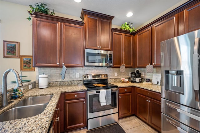 kitchen with sink, decorative backsplash, light stone countertops, light tile patterned flooring, and stainless steel appliances