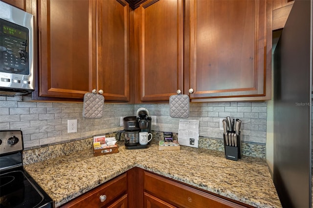 kitchen featuring decorative backsplash, stainless steel appliances, and light stone countertops