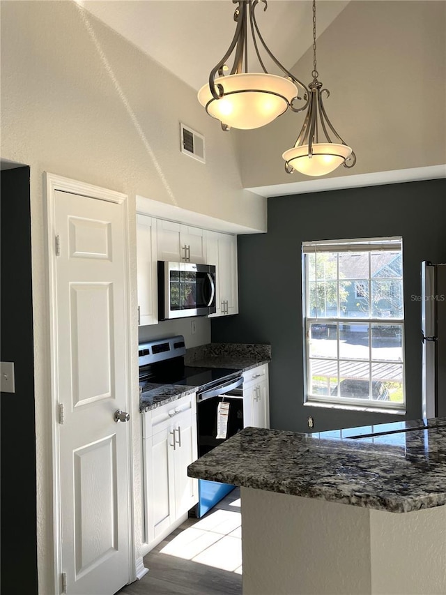 kitchen featuring white cabinets, hanging light fixtures, light hardwood / wood-style flooring, vaulted ceiling, and stainless steel appliances