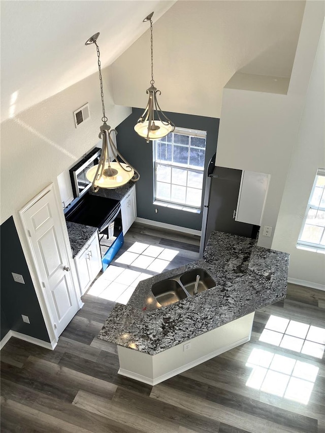 kitchen with sink, pendant lighting, high vaulted ceiling, hardwood / wood-style floors, and white cabinetry