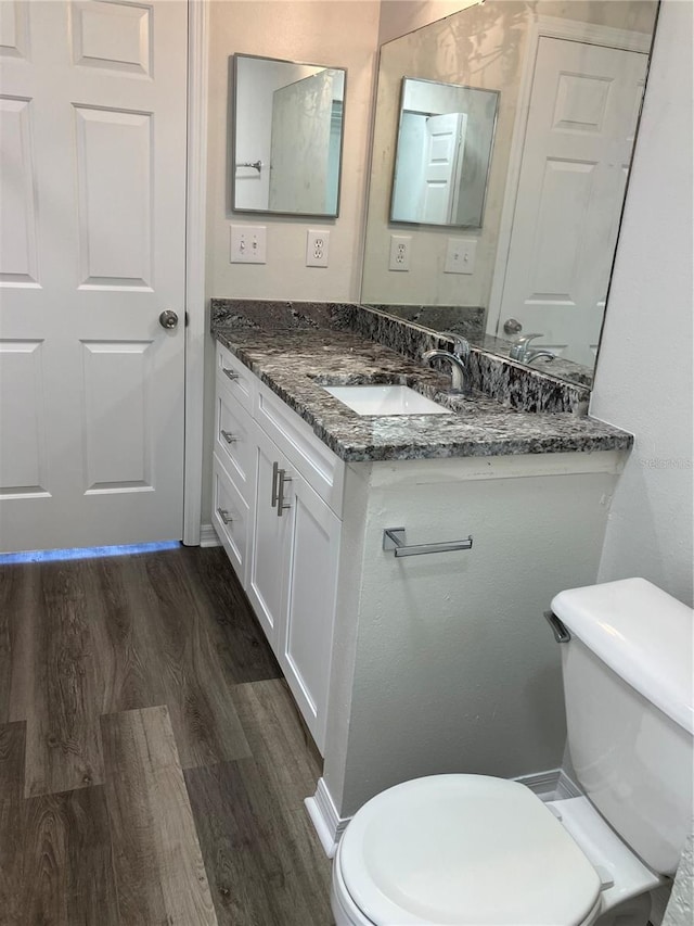 bathroom with hardwood / wood-style floors, vanity, and toilet