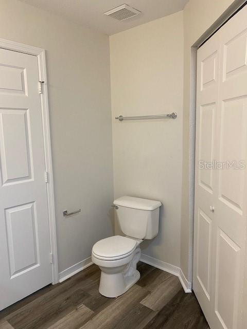 bathroom featuring toilet and wood-type flooring