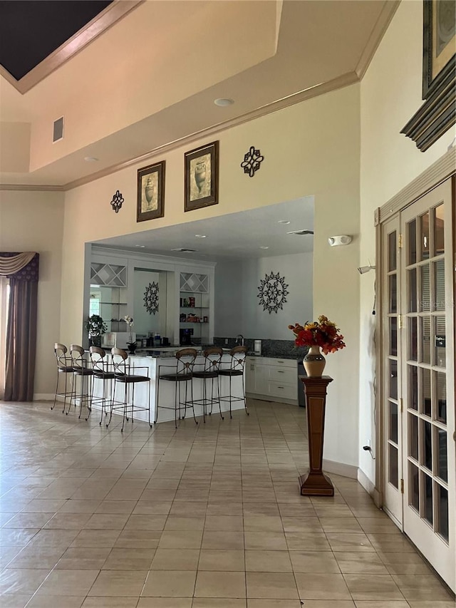 interior space with a kitchen bar, a tray ceiling, and light tile patterned floors