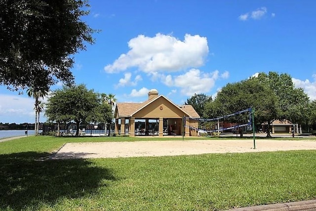 view of community with volleyball court, a lawn, and a water view