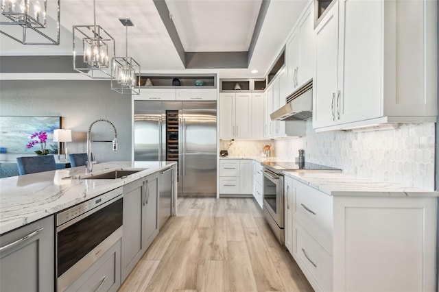 kitchen featuring stainless steel appliances, white cabinetry, light stone countertops, and sink