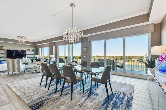 dining room with a notable chandelier, ornamental molding, hardwood / wood-style floors, and a water view