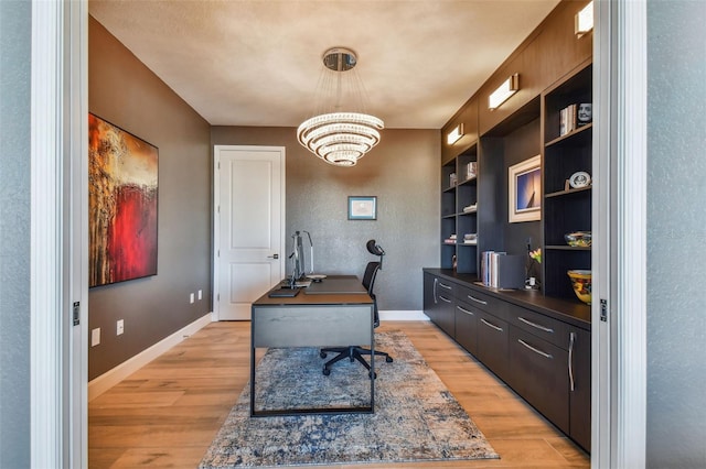 office with built in shelves, light hardwood / wood-style flooring, and a chandelier