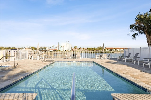 view of pool with a water view and a patio