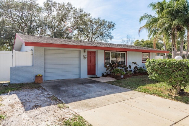 ranch-style house with concrete driveway, brick siding, an attached garage, and fence