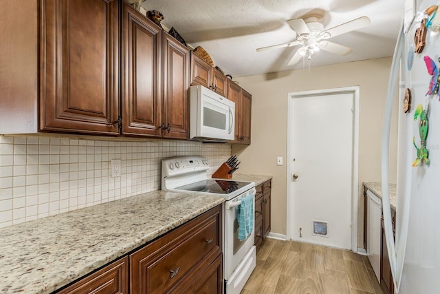 kitchen featuring white appliances, a ceiling fan, baseboards, light stone countertops, and tasteful backsplash