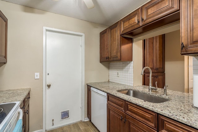 kitchen with tasteful backsplash, light wood-style flooring, a sink, light stone countertops, and white appliances