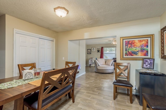 dining area with a textured ceiling, wood finish floors, a ceiling fan, and baseboards