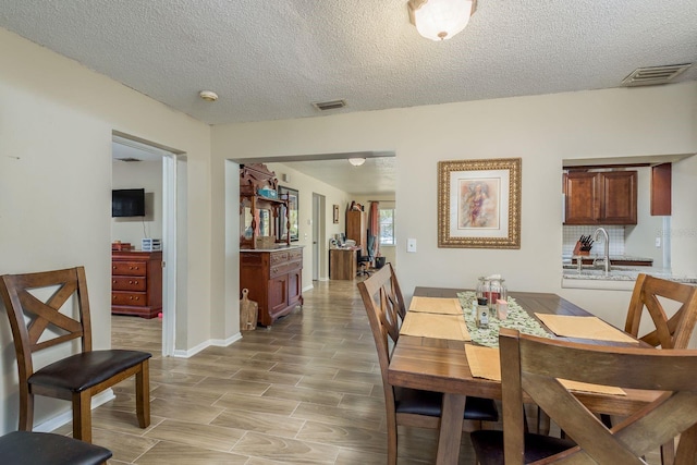 dining room featuring visible vents, a textured ceiling, and baseboards