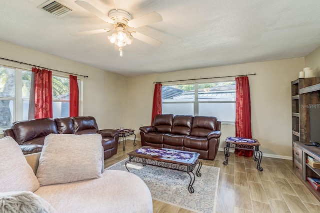 living room with visible vents, a ceiling fan, a textured ceiling, wood finished floors, and baseboards