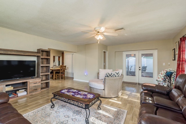 living area with a textured ceiling, ceiling fan, visible vents, french doors, and wood tiled floor