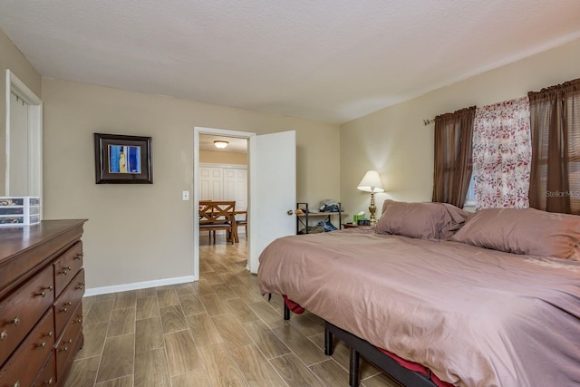 bedroom with wood tiled floor, baseboards, and a textured ceiling