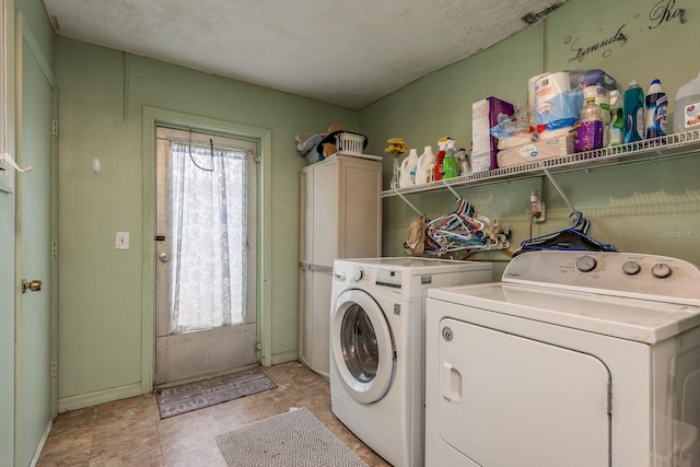 laundry room featuring a textured ceiling, baseboards, washing machine and dryer, and a healthy amount of sunlight