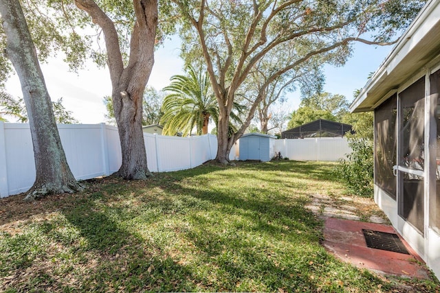 view of yard featuring a sunroom, a fenced backyard, an outdoor structure, and a storage shed