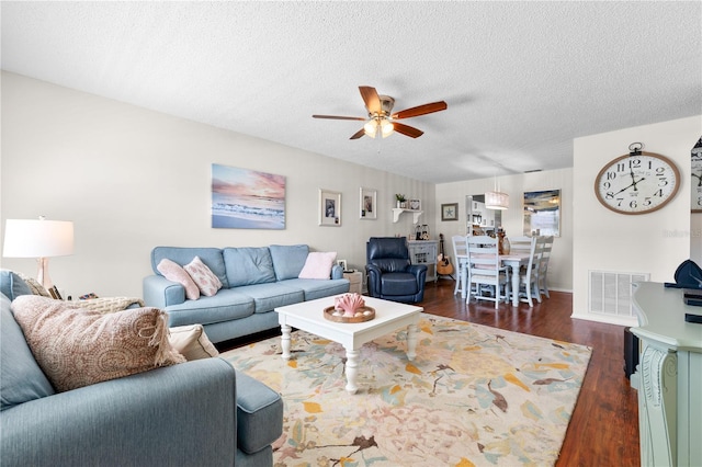 living room featuring a textured ceiling, ceiling fan, and dark hardwood / wood-style floors