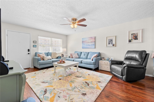 living room with a textured ceiling, ceiling fan, and dark wood-type flooring