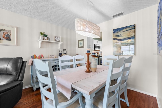 dining area featuring dark hardwood / wood-style flooring and a textured ceiling