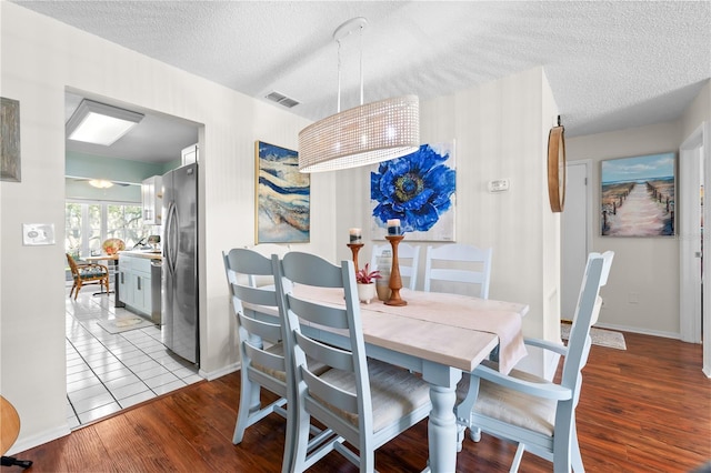 dining space with a textured ceiling and light hardwood / wood-style flooring