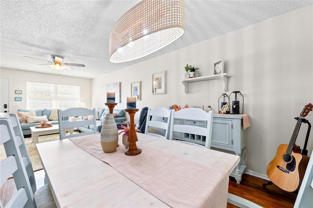 dining room with a textured ceiling, ceiling fan, and dark wood-type flooring