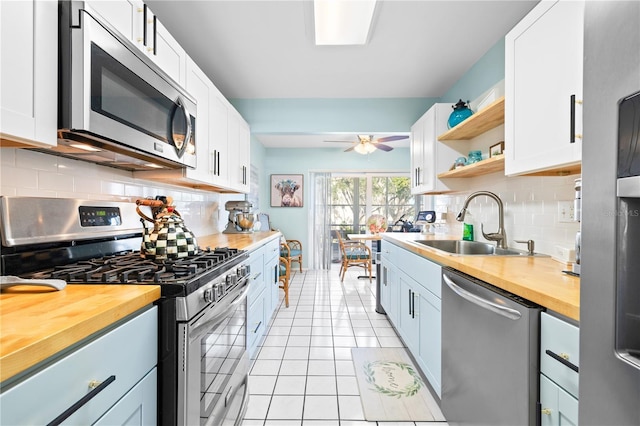 kitchen with white cabinets, ceiling fan, light tile patterned floors, butcher block counters, and stainless steel appliances