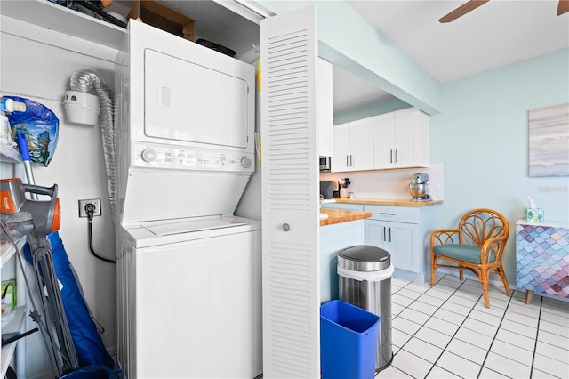 clothes washing area featuring ceiling fan, light tile patterned floors, and stacked washer and clothes dryer