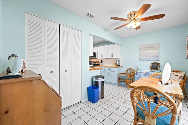 dining room featuring ceiling fan, light tile patterned floors, and a textured ceiling