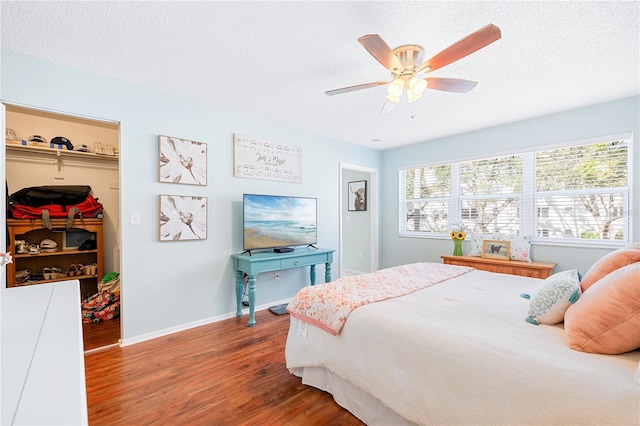 bedroom with hardwood / wood-style flooring, ceiling fan, a textured ceiling, and a closet