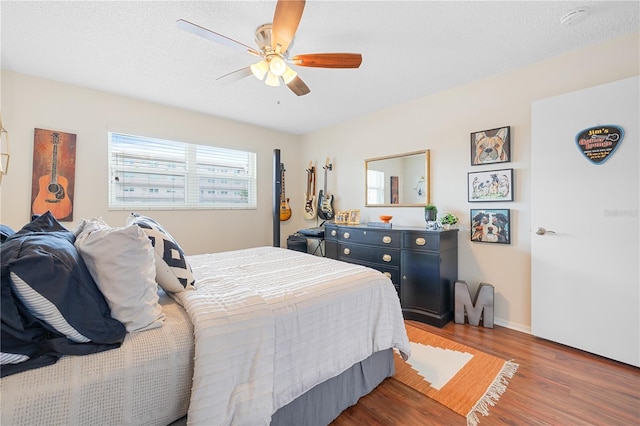 bedroom with hardwood / wood-style floors, a textured ceiling, and ceiling fan