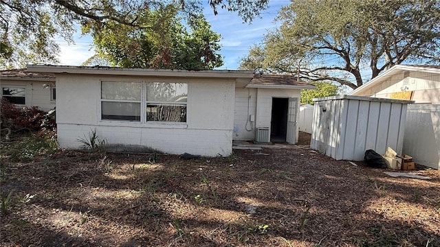 rear view of property featuring cooling unit and a storage shed