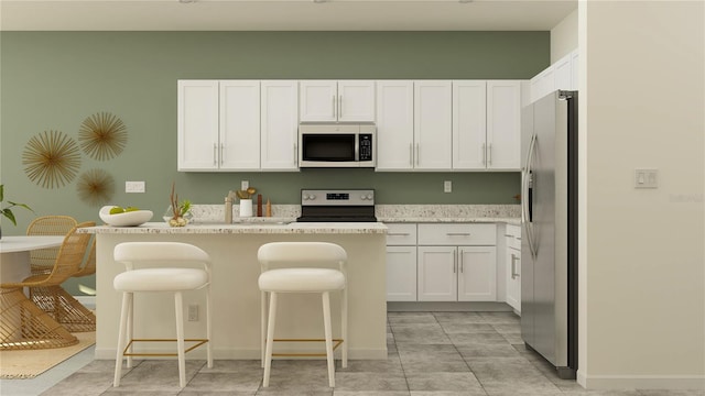 kitchen featuring a breakfast bar area, light stone countertops, a kitchen island, white cabinetry, and stainless steel appliances