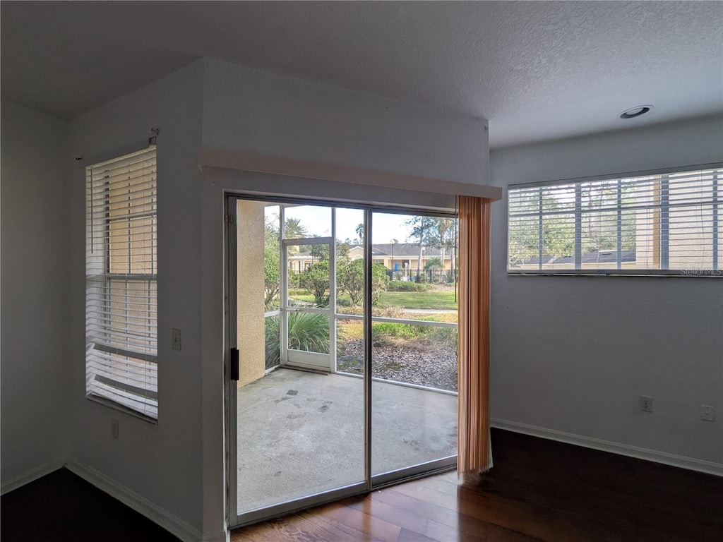 doorway to outside with a textured ceiling and hardwood / wood-style flooring