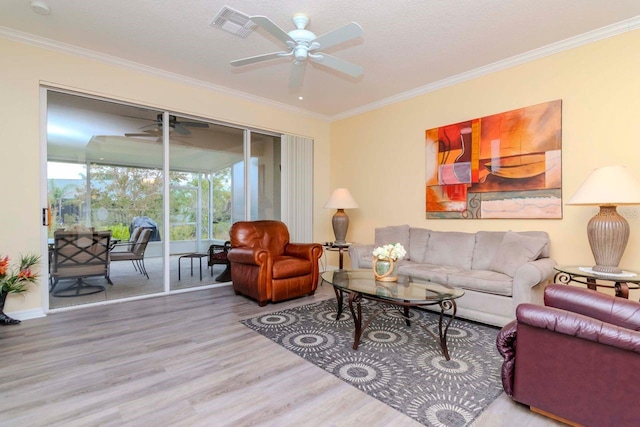 living room featuring hardwood / wood-style floors, ceiling fan, ornamental molding, and a textured ceiling