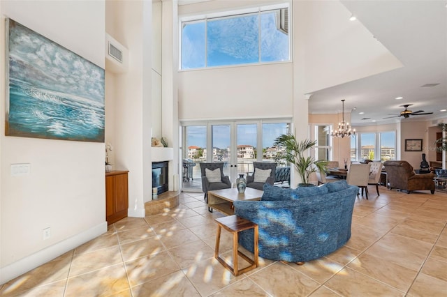 living room with tile patterned floors, a high ceiling, and ceiling fan with notable chandelier