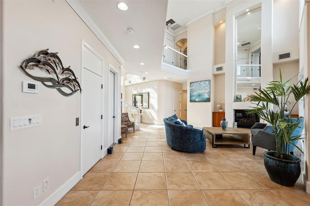 interior space with light tile patterned flooring, ornamental molding, and a towering ceiling